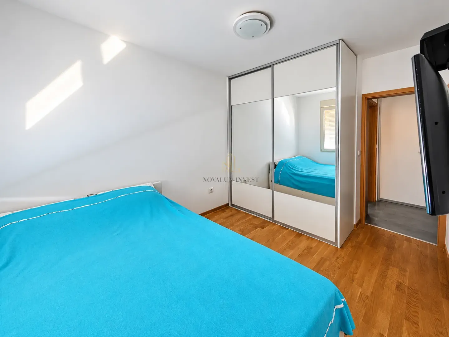 Bedroom with a double bed, large wardrobe, and wooden flooring.