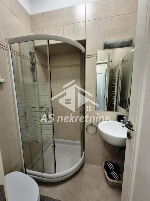Smaller bathroom with a shower cabin, washbasin, and tiled walls.