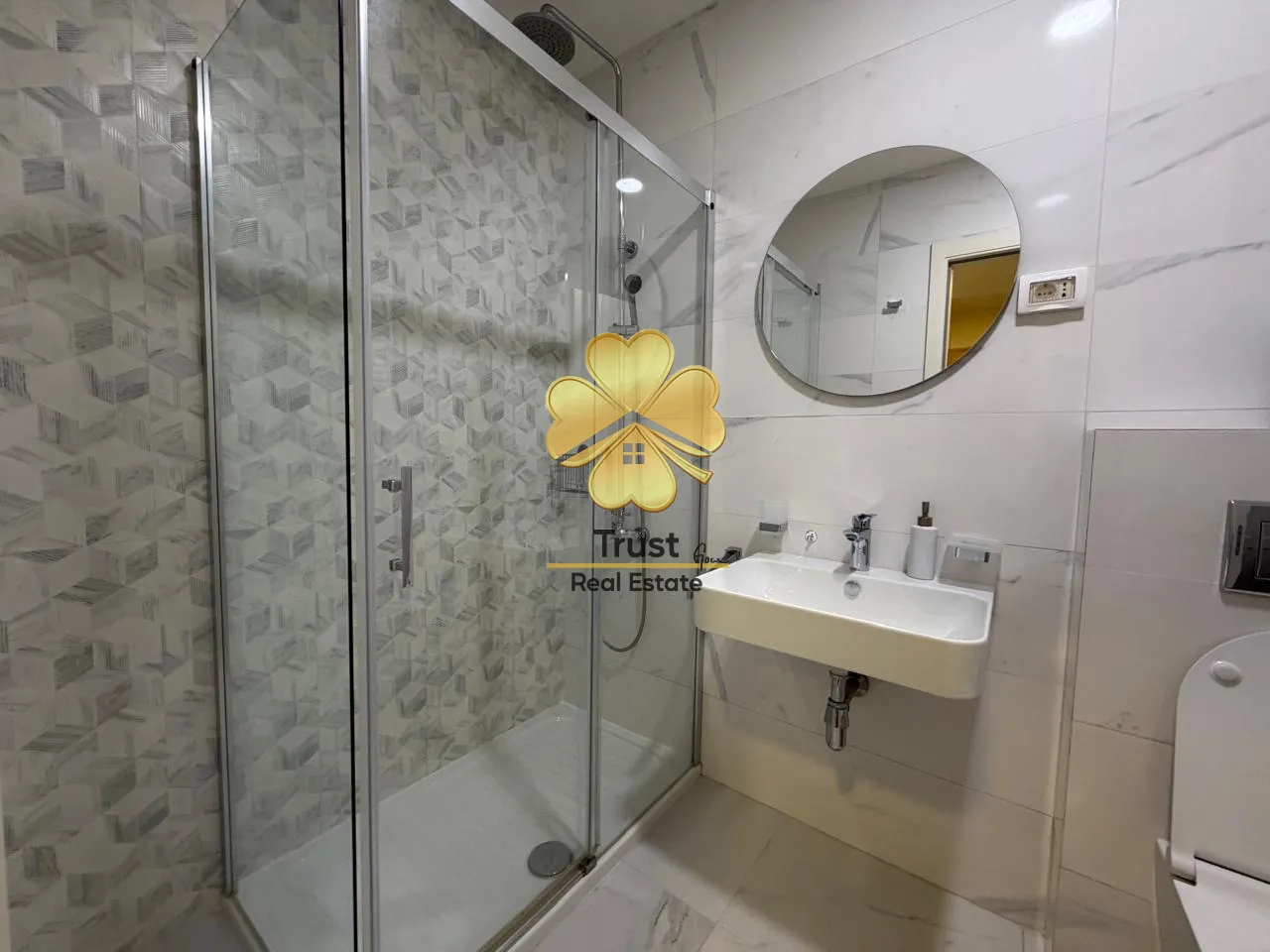Modern bathroom with a shower cabin, washbasin, and mirror.
