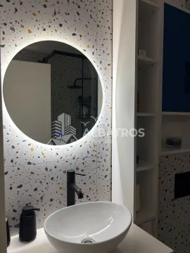 Modern bathroom with a washbasin, round illuminated mirror, and shelving. - image 11
