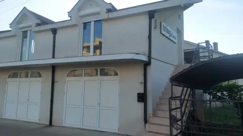 Exterior view of a small commercial and residential building with an outdoor staircase and ground floor doors. - image 6