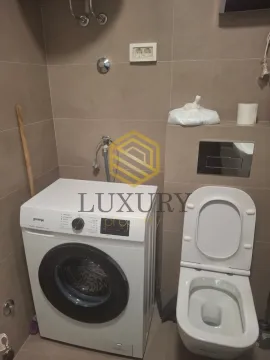 Bathroom with a washing machine and toilet. - image 8