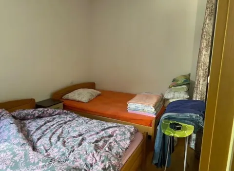 Bedroom with two beds and folded bedding. - image 4