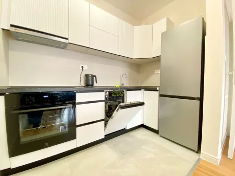 Modern white kitchen with built-in appliances and a refrigerator. - image 8