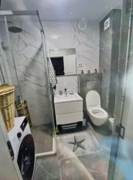 Modern bathroom with a walk-in shower, washbasin, toilet, and washing machine. - image 5