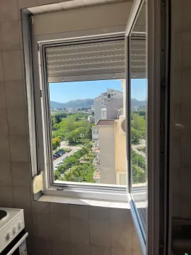 Pogled kroz otvoreni prozor na zelenilo i okolne zgrade. - image 3