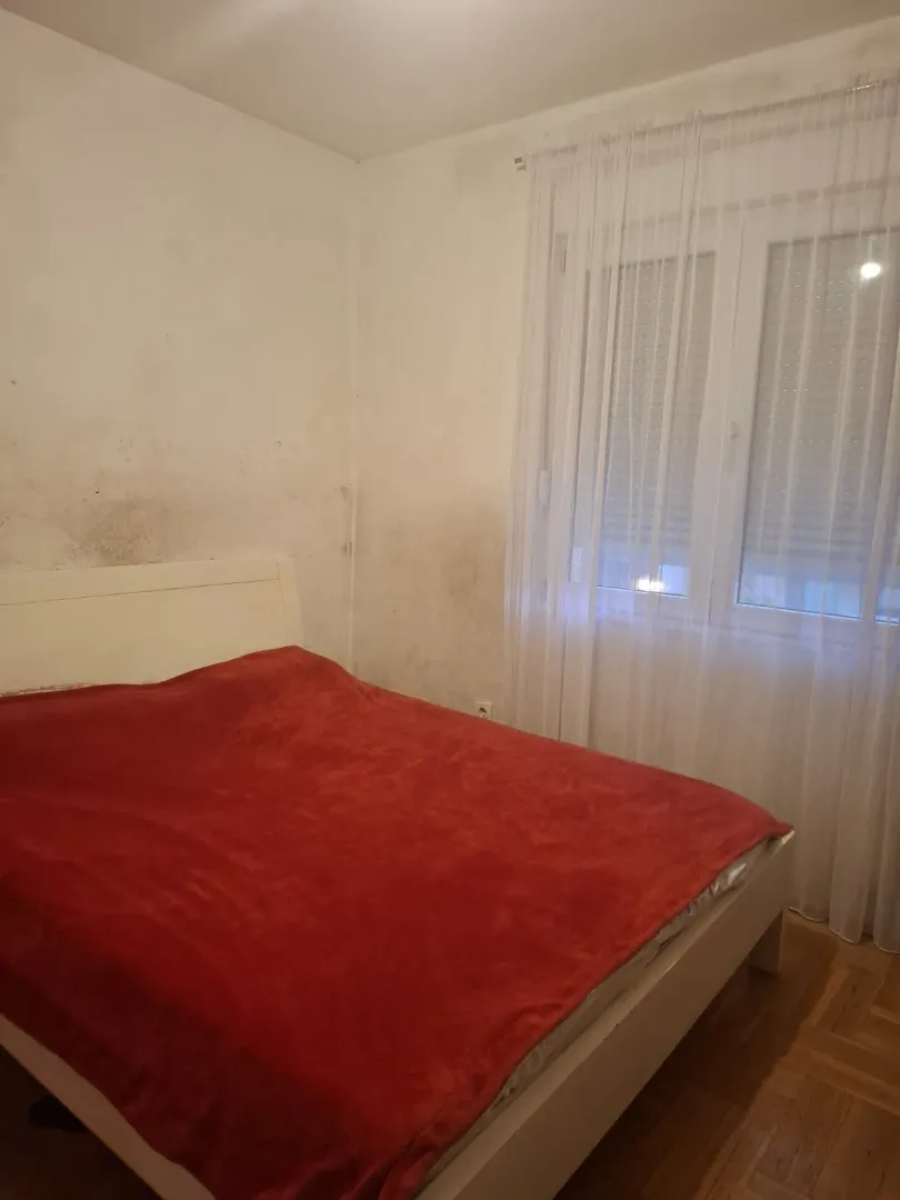 Jednostavna spavaća soba sa bračnim krevetom i prozorom.