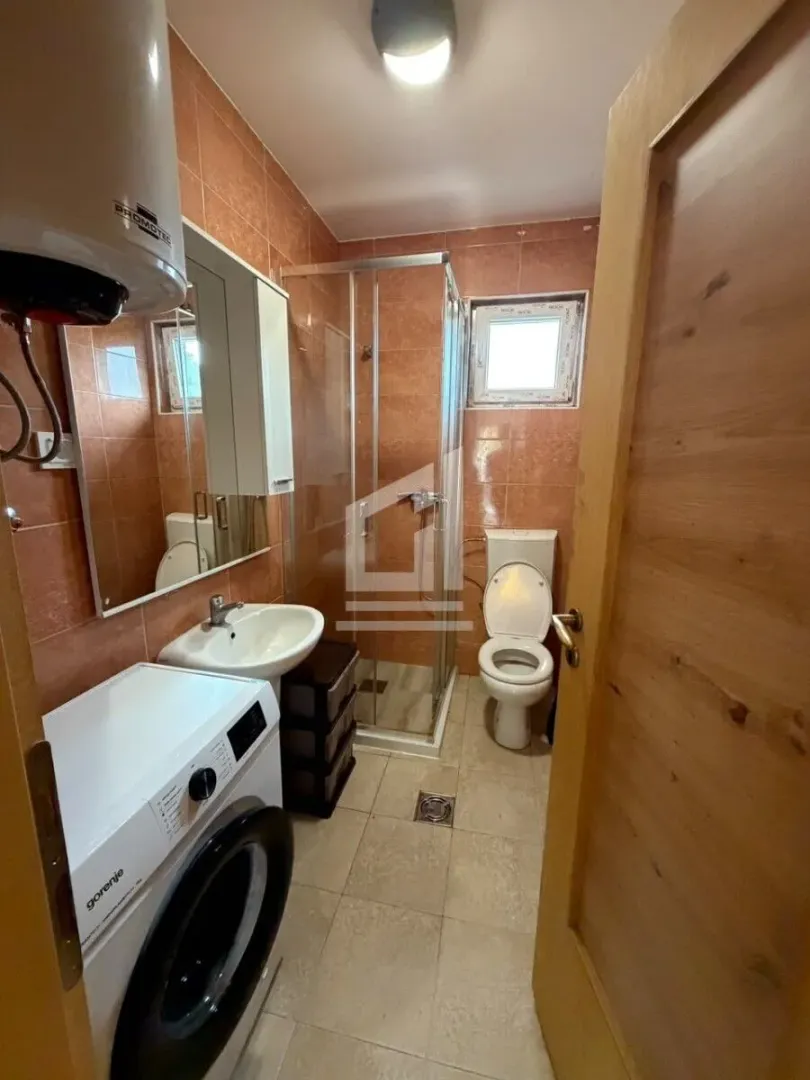 Bathroom with a shower cabin, washbasin, toilet, and washing machine.