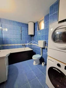 Kupatilo obloženo plavim pločicama sa kadom, toaletom i mašinama za pranje i sušenje veša. - image 11