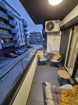Namešten balkon sa garniturom za sedenje i pogledom na naselje i parking. - image 3