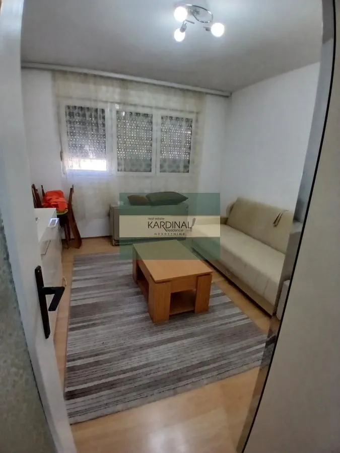 Dnevna soba sa garniturom za sedenje, stočićem i prozorom.