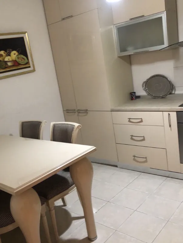 Kuhinja sa elementima u bež boji i trpezarijskim stolom.