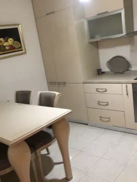 Kuhinja sa elementima u bež boji i trpezarijskim stolom. - image 7