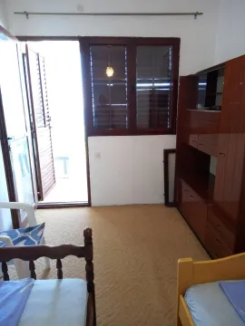 Spavaća soba sa krevetima, drvenim ormarom i izlazom na terasu. - image 7