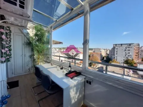 Zastakljeni balkon sa stolom i pogledom na grad. - image 11