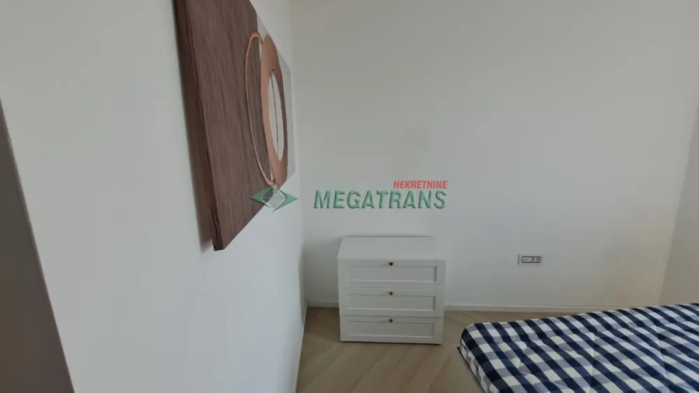 Pogled na deo spavaće sobe sa krevetom i belom komodom.