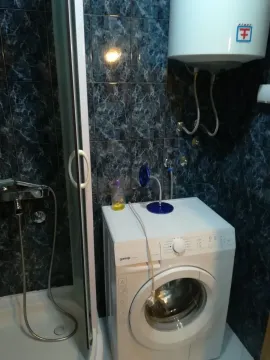 A bathroom featuring a shower cabin, washing machine, and water heater. - image 8