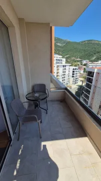 Covered balcony with outdoor seating and a view of surrounding buildings and hills. - image 18