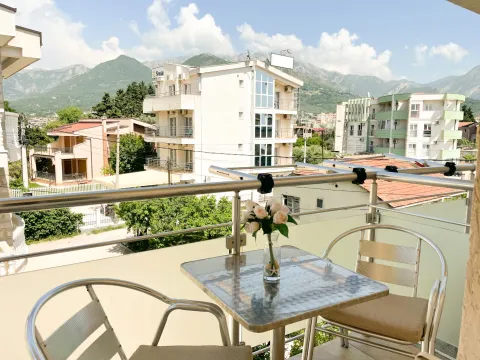 Furnished balcony with a table, chairs, and a view of surrounding buildings and mountains. - image 8
