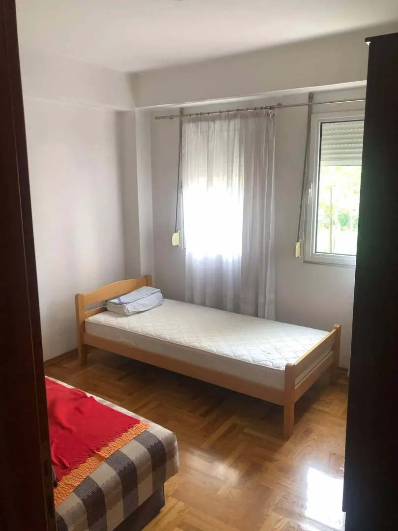 Manja spavaća soba sa drvenim krevetom i parketom.