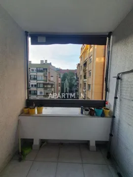 Manji zatvoreni balkon sa pogledom na okolne zgrade i saksijama sa cvećem. - image 8