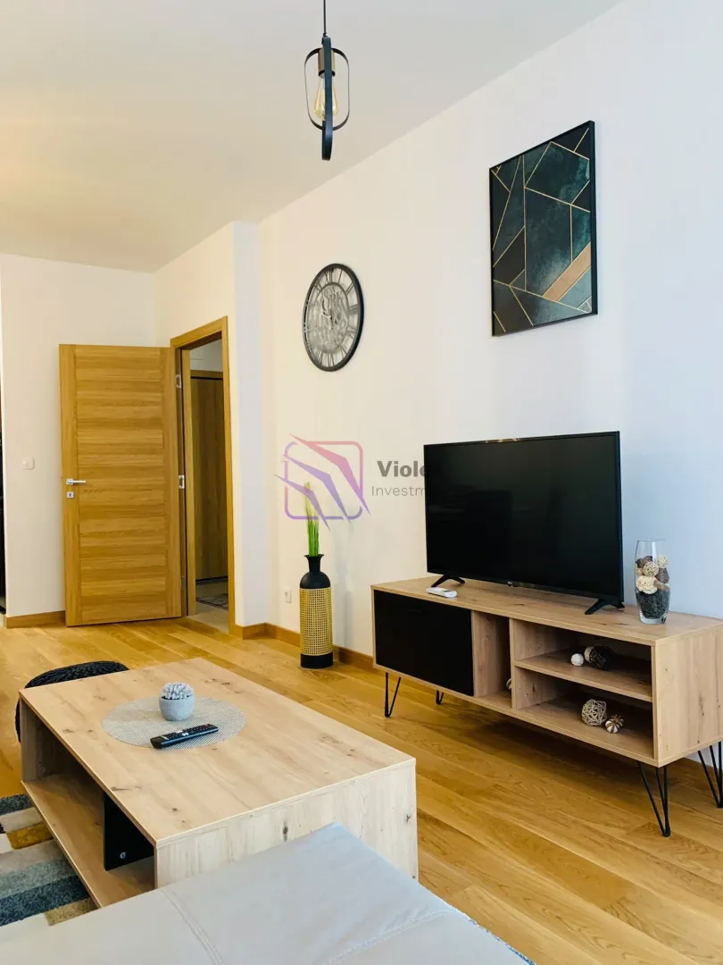 Living room with wooden floor, TV and coffee table.
