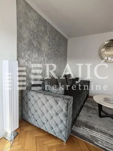 Furnished living room with a corner sofa and a decorative wall.