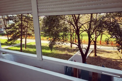Pogled sa terase na uređeni park i zelenilo ispred zgrade. - image 3