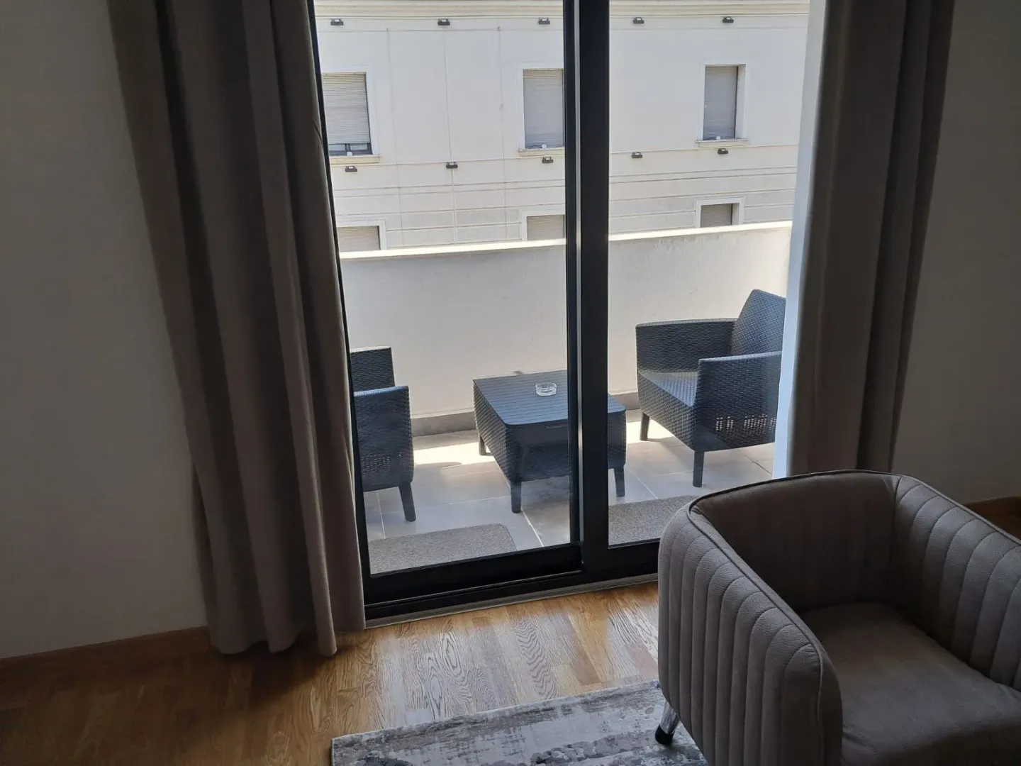 View from the room onto the furnished balcony with seating set.