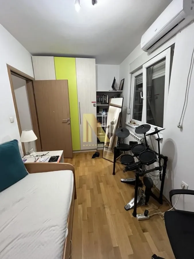 Dečja soba sa krevetom, ormarom, radnim stolom i elektronskim bubnjevima.