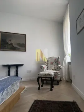 Spavaća soba sa krevetom, foteljom i umetničkim slikama na zidu. - image 12