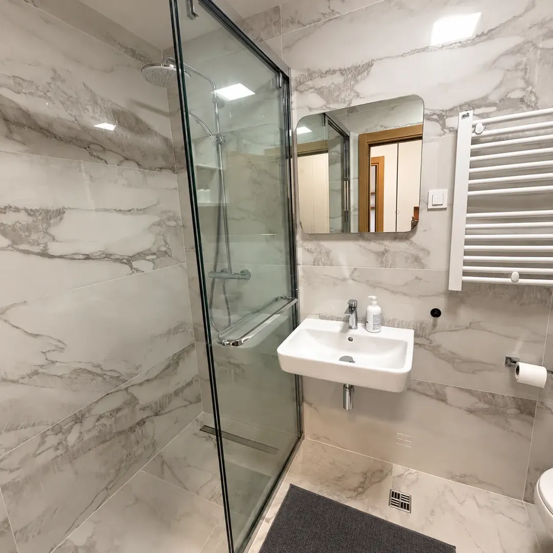 Modern bathroom with a marble-tiled shower cabin and a washbasin.