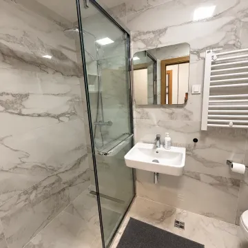 Modern bathroom with a marble-tiled shower cabin and a washbasin. - image 8