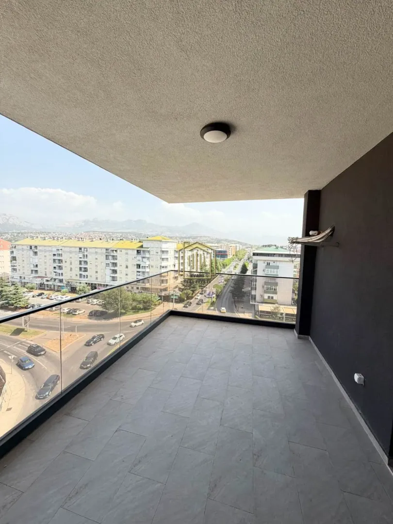 Spacious covered balcony with a glass railing and city views.