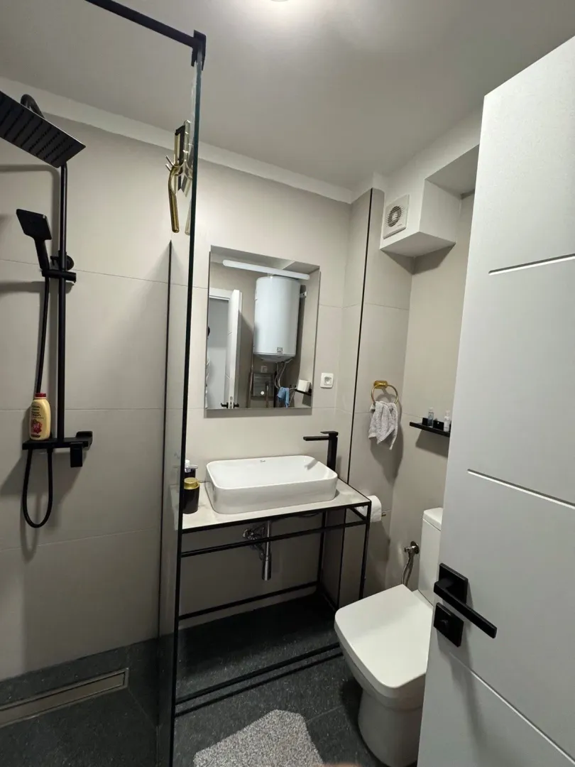 Moderne kupatilo sa tuš kabinom, umivaonikom i wc šoljom.