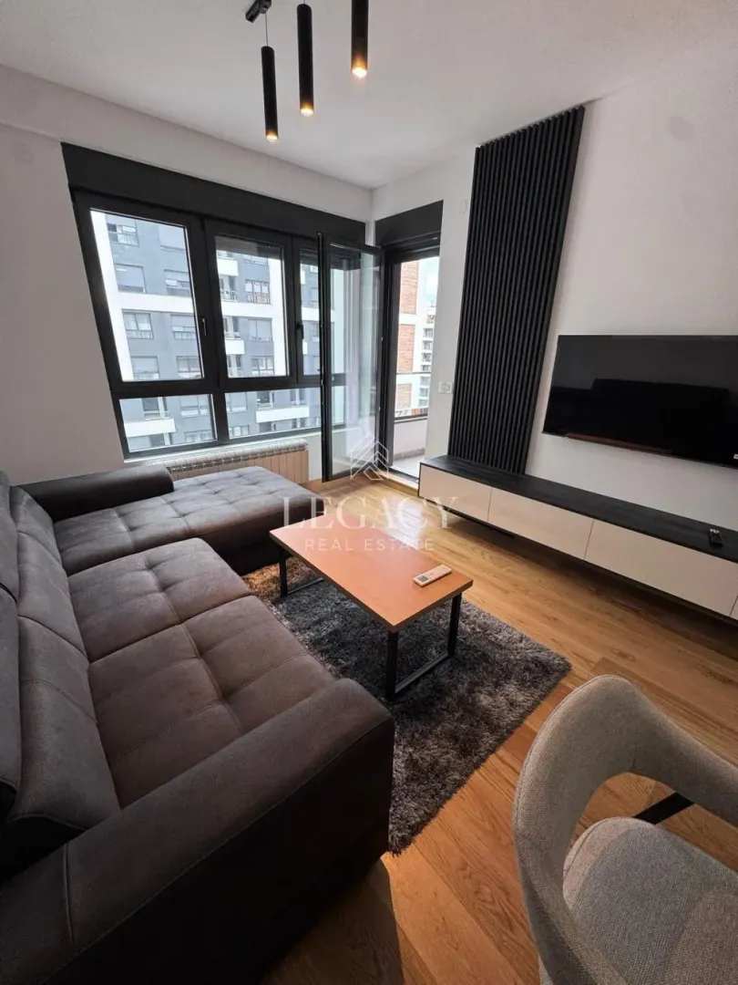 Moderna dnevna soba sa garniturom, TV-om i izlazom na terasu.