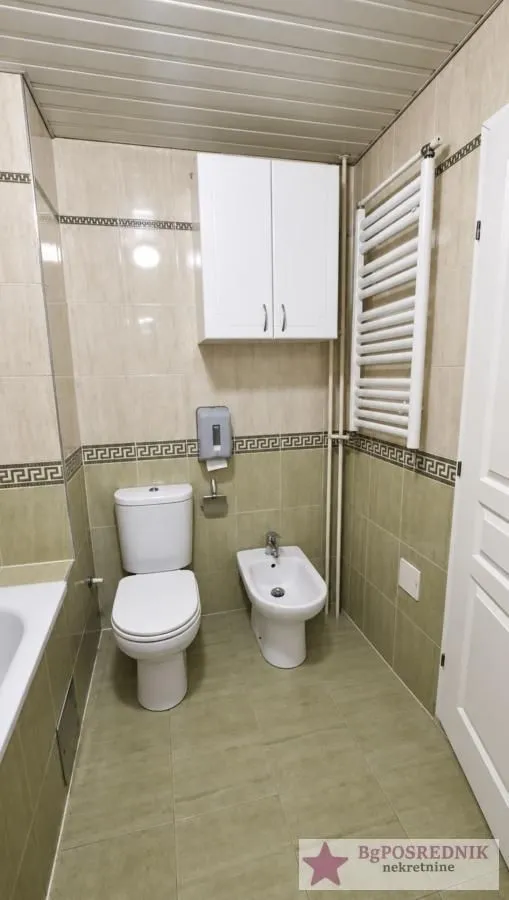 Bathroom equipped with a toilet, bidet, wall cabinet, and radiator.