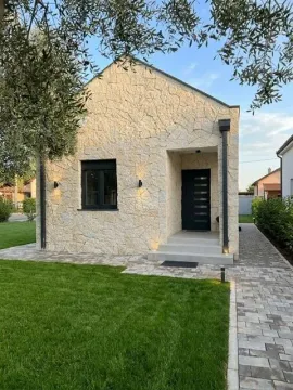 Front view of a modern single-story stone-clad house with a landscaped yard. - image 10