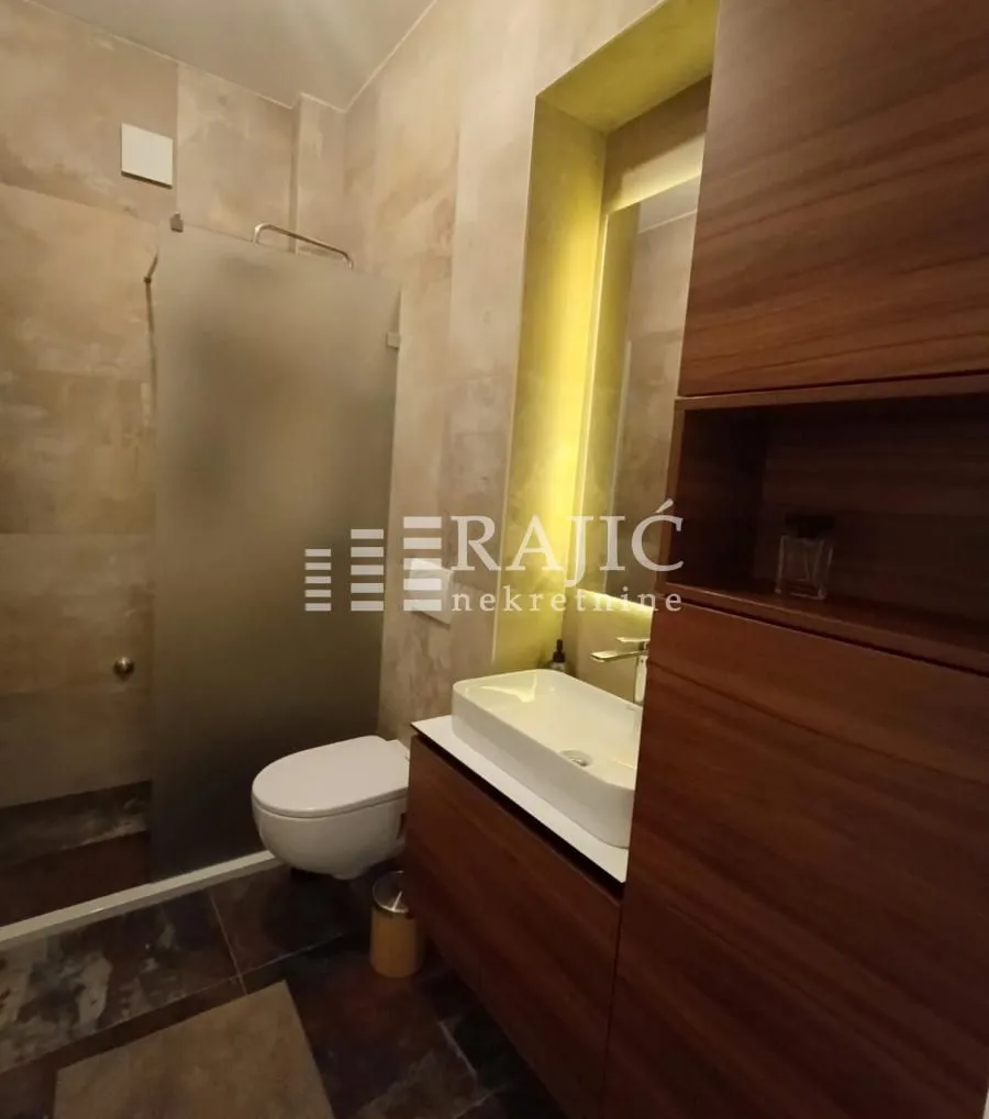 Modernly equipped bathroom with a washbasin and walk-in shower.
