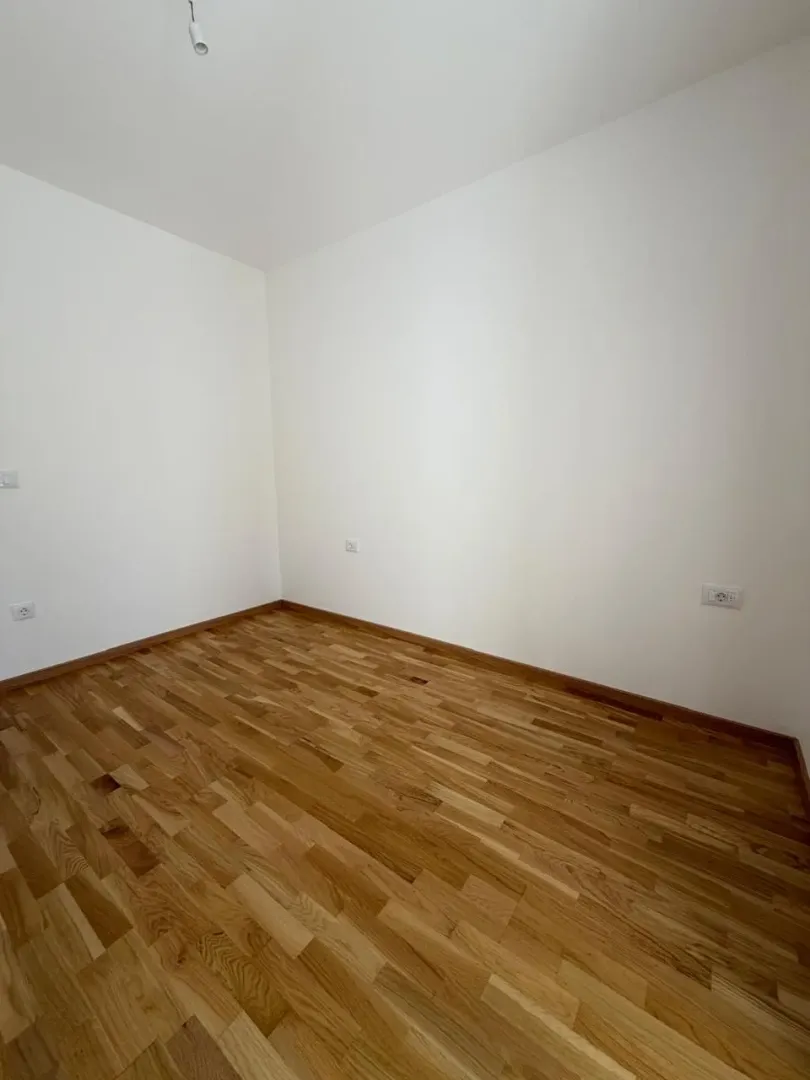 Prazna soba sa bijelim zidovima i parketom.