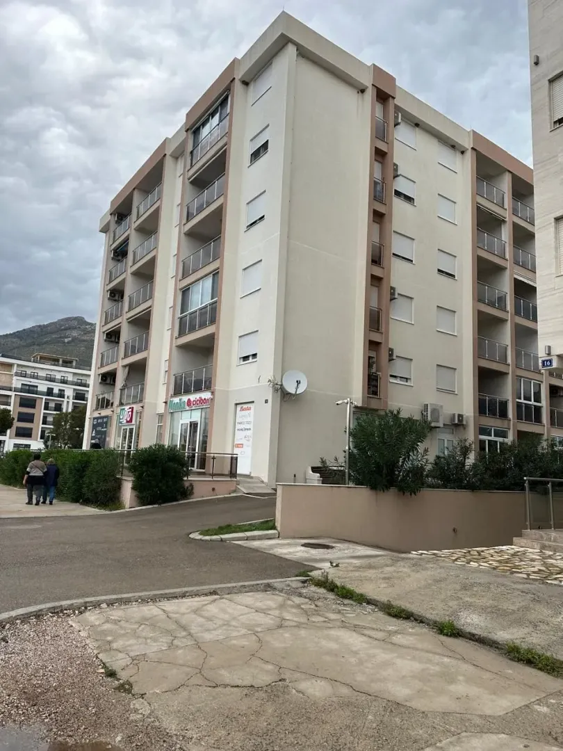 Spoljašnji izgled stambene zgrade sa prilazom i okolnim rastinjem.