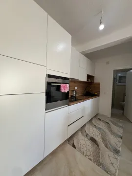 Modern white kitchen with a built-in oven and wooden countertop. - image 6