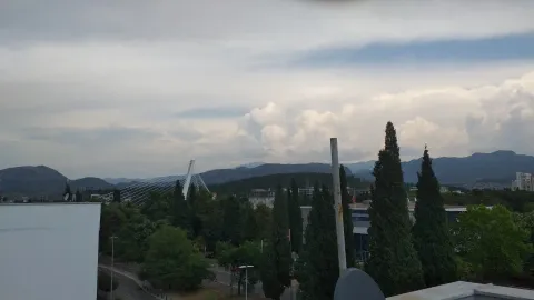 Elevated view of the city, bridge, and hills in the distance under a cloudy sky. - image 4