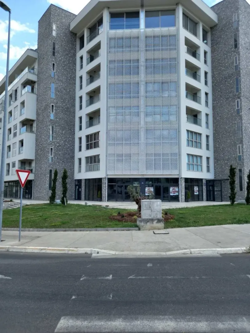 View of a modern residential building with a stone facade and large glass surfaces.