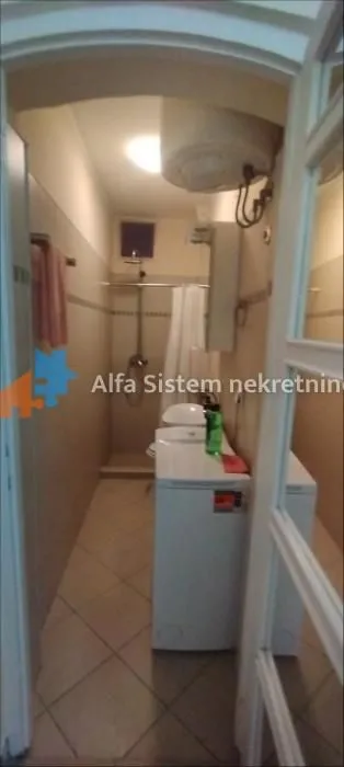 View of the bathroom with a shower cabin, sanitary ware, and a washing machine.