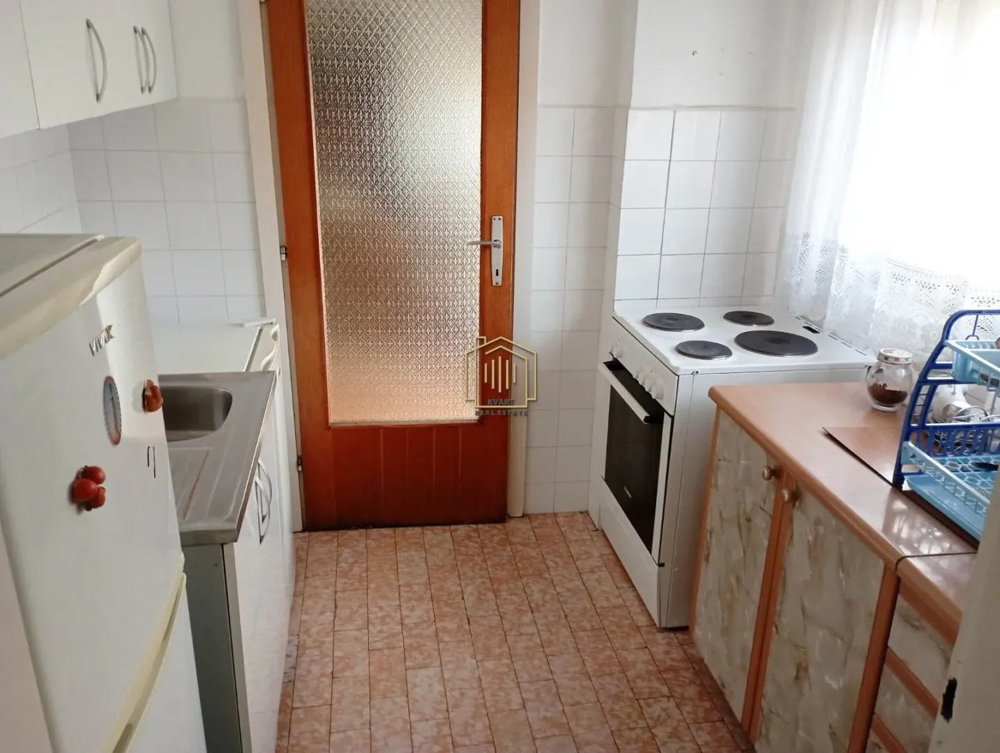 Small kitchen with white cabinets, stove, and refrigerator.