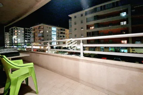 Natkriveni balkon sa garniturom za sjedenje i pogledom na okolne zgrade noću. - image 2