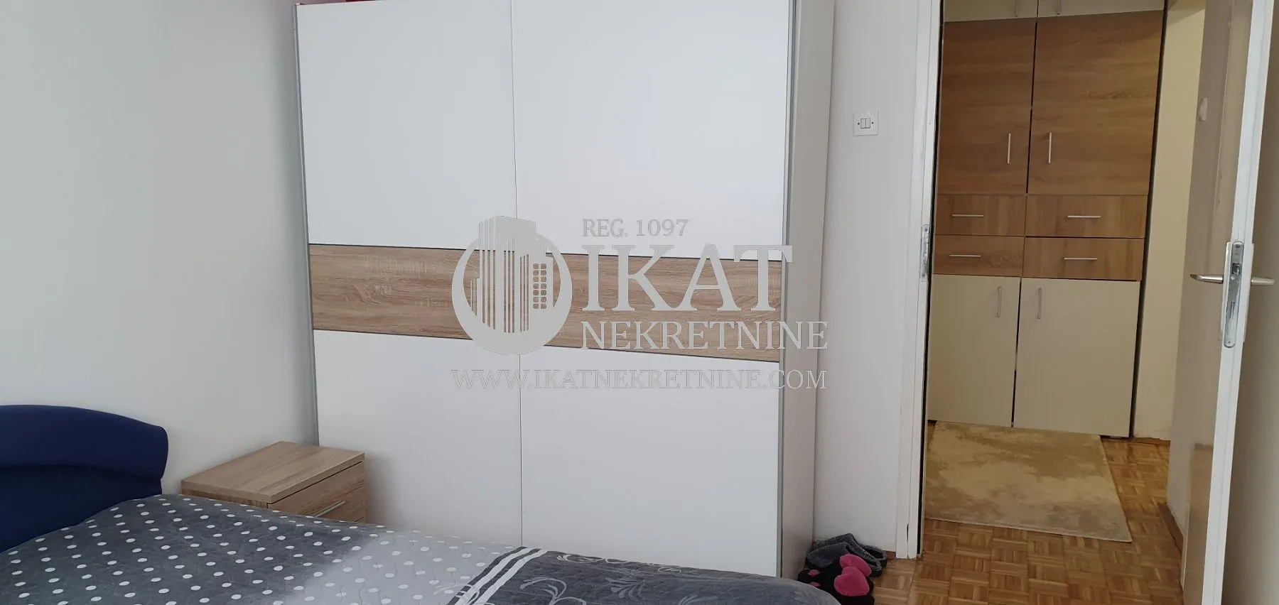 Bedroom with a large white wardrobe and a bed.