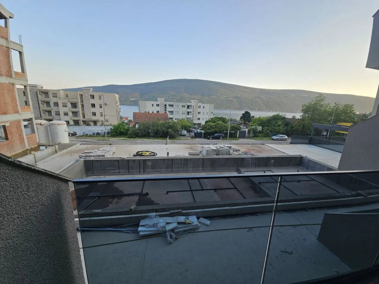 Pogled sa terase na naselje, okolne zgrade i planinu u pozadini.