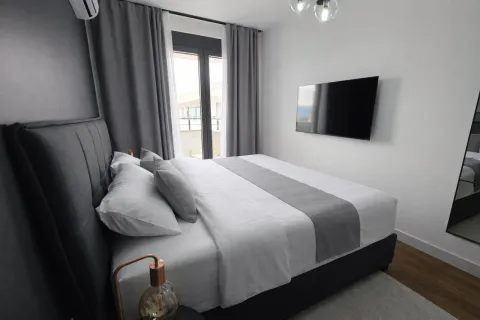 Modern bedroom with a double bed, grey curtains, and a wall-mounted TV. - image 8